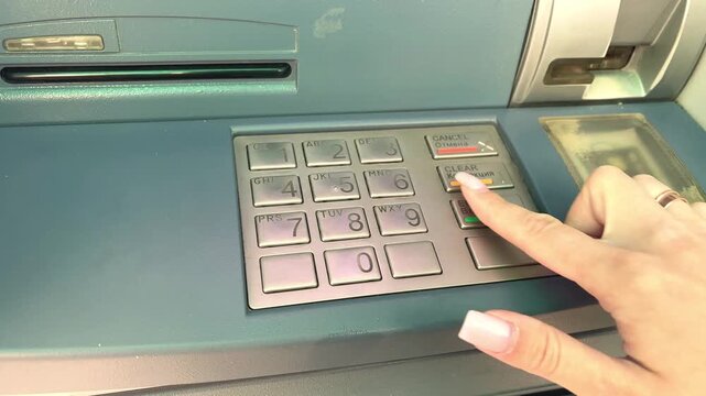 Woman entering pin on atm keypad for banking transaction