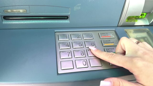 Woman's hand with long nails pressing buttons on an atm keypad during a financial operation