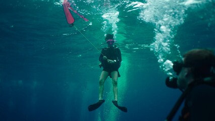 Scuba diver deploying a surface marker buoy in clear blue water © FranciscoJavier