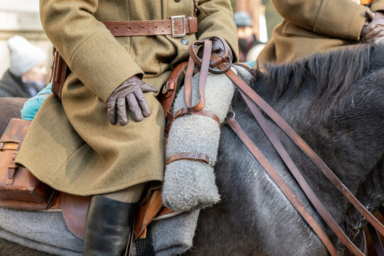 Anonymous cavalry soldier in vintage uniform riding dark horse, closeup of leather saddle, reins, gloves and wool blanket at public parade, military reenactment equestrian heritage and history concept