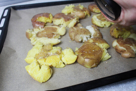 Cooking crispy roasted smashed baked potatoes. Sprinkles pepper on potatoes
