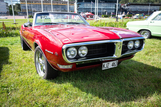Stockholm, Sweden - August 2, 2025: Red 1968 Pontiac Firebird convertible with quad headlights and chrome split grille, front three-quarter view at Stockholm Car Meet