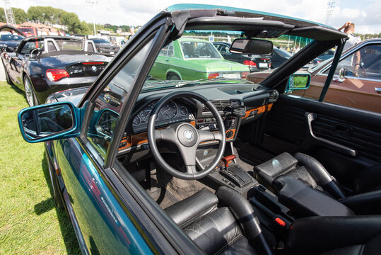 Stockholm, Sweden - August 5, 2023: Teal BMW E30 3 Series convertible interior with wood trim dashboard, leather seats and classic steering wheel at Stockholm Car Meet