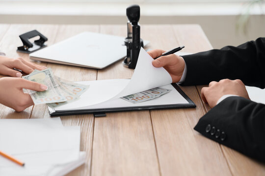 Hands exchanging money and documents on a wooden desk bribery corruption and illegal financial transactions, the interaction suggests a clandestine deal or unethical business practice