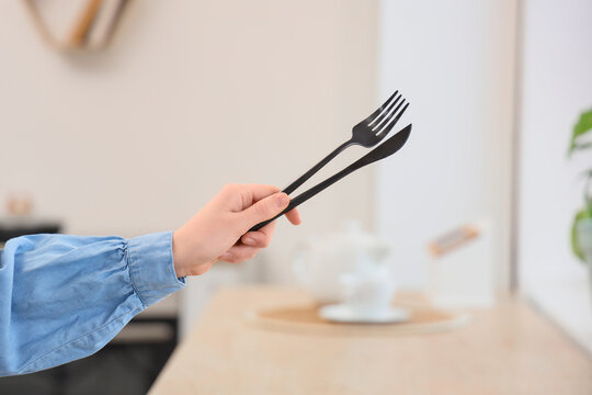 Person holding black plastic fork and knife, disposable cutlery for dining and takeaway food service