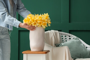 Obraz premium Woman with daffodils in vase at home, closeup