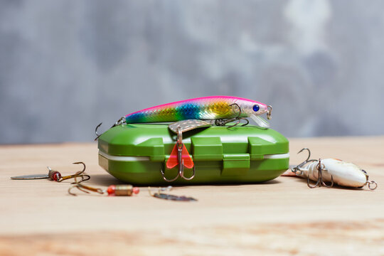 Artificial fishing lures with colorful wobbler minnow on green tackle box. Angling equipment, predator fish tackles or sport fishing kit for retail website banner template copy space.
