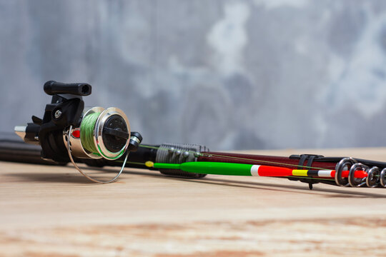 Telescopic fishing rod with spinning reel, braided line and colorful float setup on wooden table. Angling tackle kit, sport fishing equipment retail or outdoor recreation gear concept.