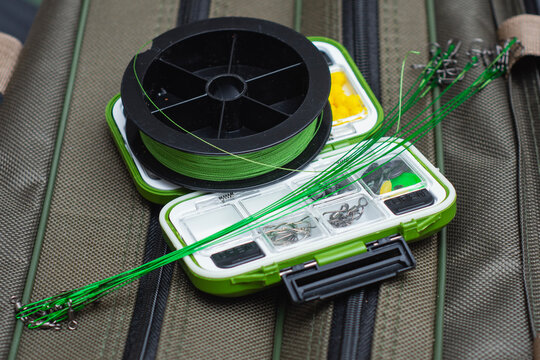 Fishing tackle box with braided fishing line spool and wire leaders on a gear bag. Freshwater angling equipment for fishing preparation, outdoor recreation and sport fishing.