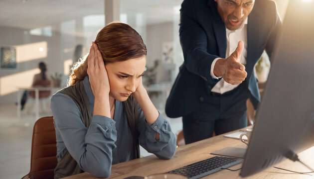 Stressed businesswoman covering her ears while an angry male boss shouts and points at a computer screen in the office, symbolizing workplace conflict, toxic leadership, and stress