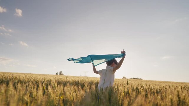 Little boy runs through golden wheat field holding Kazakhstan national flag, summer sunset. Kazakh heritage, agricultural traditions, rural life and country vast grain-producing steppes.