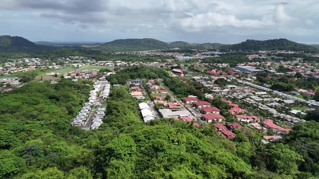 Smooth aerial drone flight over Montjoly with tropical forest, residential area and hills in French Guiana.