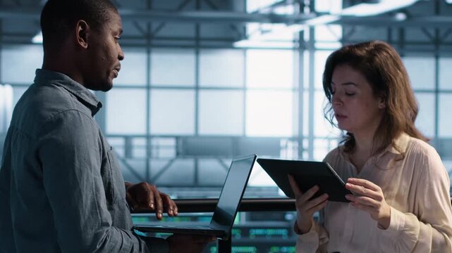 Data scientists use laptop and tablet in a server farm to perform vulnerability scans and verify firewall security, combining vulnerability scanning, security patch and firewall security.