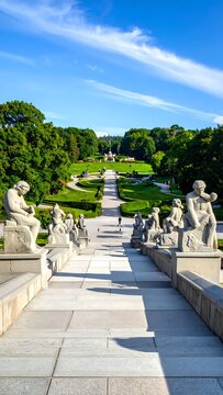 Grand Staircase with Statues Overlooking a Lush Park Under Blue Sky