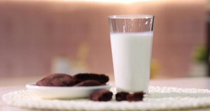 Woman putting glass of fresh milk onto table in kitchen, closeup. Camera moving forward