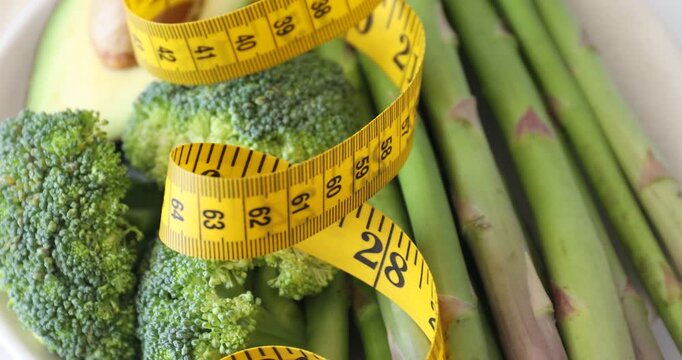 Measuring tape and healthy products on table, spinning. Closeup view
