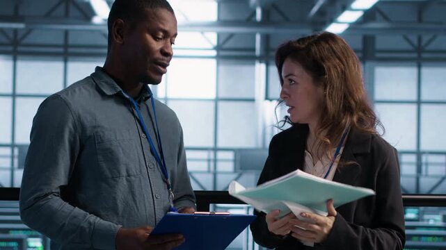 IT colleagues use documents in a server farm to review technical documentation and system reports, combining documentation review, document review and maintenance reports.