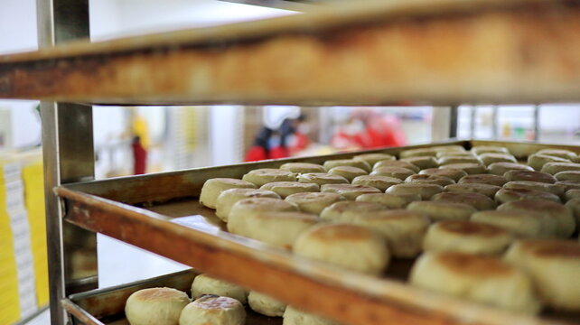 Rows of freshly made bakpia sit on bakery trays, highlighting traditional Indonesian pastry production, baking expertise, and food preparation.