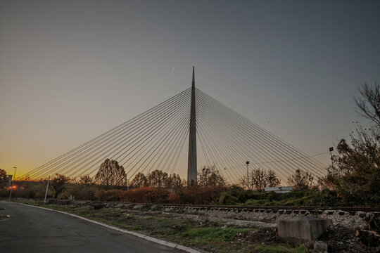Ada Bridge, or Most na Adi, seen at dusk with its central pylon, radiating suspension cables, railway tracks and the Sava River area framing a modern city landmark in the Serbian capital in Belgrade.