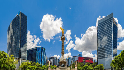 Mexico City skyline as viewed from the Paseo de la Reforma in front of The Angel of the Independence monument, surrounded by skyscrapers, on a sunny day. © mandritoiu