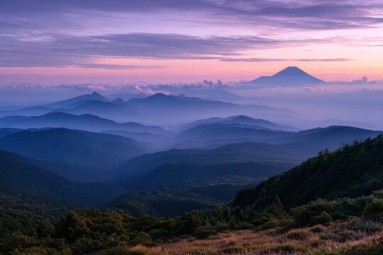 Breathtaking sunset view over layered mountain peaks and soft valley mist in purple light with mountain landscape wilderness atmosphere beautiful majestic exploration topography colorful