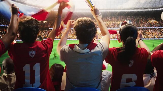 Soccer fans waving scarves during match played on crowded stadium turf, showing football supporters in grandstands singing, creating electric stadium atmosphere, concept of team support.