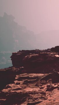 Rugged cliffs are visible in the foreground with soft hues from the sunset. Distant mountains fade into the background as daylight gives way to evening colors.