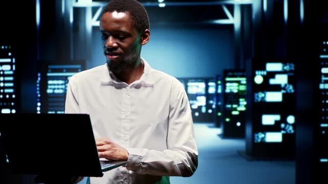 African American engineer monitors energy use and hardware status in a data center, keeping supercomputers reliable during routine data center operations during between supercomputers.