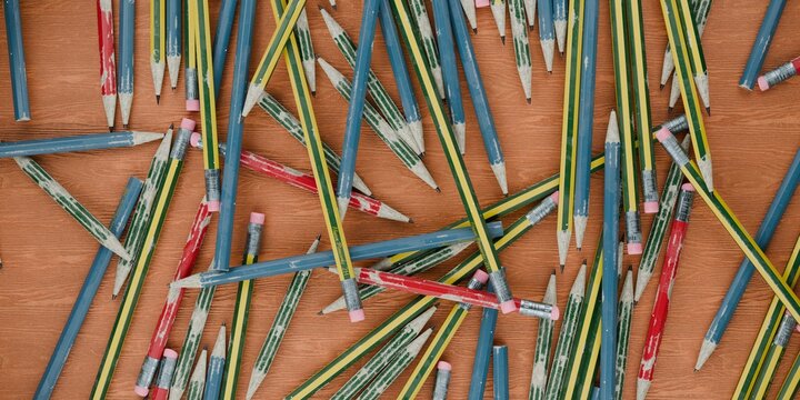 pencils scattered in a pile on a wooden school desk