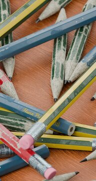 pencils scattered in a pile on a wooden school desk