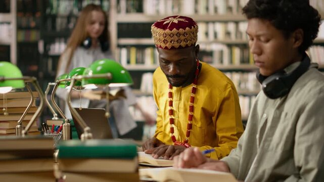 Mature adult student working at desktop and typing on keyboard, man in traditional clothing continuing education during computer class in library.