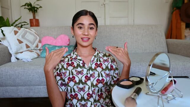 Young female vlogger talking and recording a makeup tutorial video at home