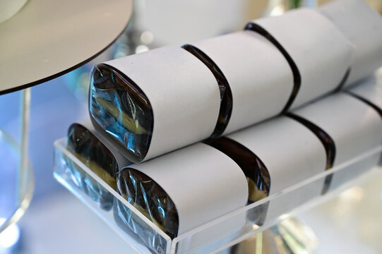wrapped chocolate brownies on elegant acrylic stand, gourmet party favours at luxury wedding dessert buffet, sweet confectionery presentation with blurred macarons tower background