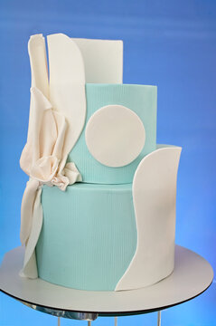 modern light blue birthday cake with white fondant details, elegant tiered wedding cake on stand, abstract luxury festive confectionery design, beautiful dessert close up