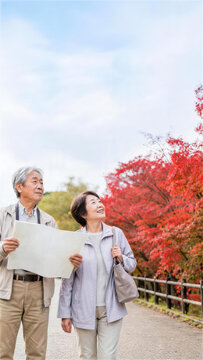 紅葉の遊歩道で地図を確認する日本人シニア夫婦