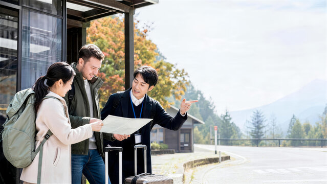 地方駅前で地図を使い外国人旅行者を案内する日本人男性ガイド