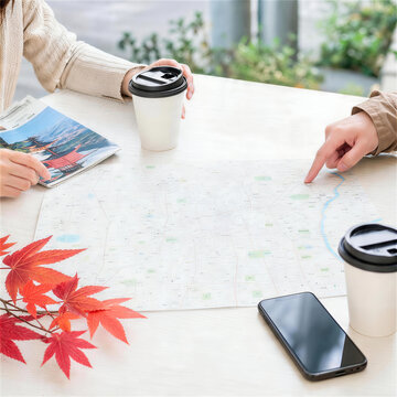 カフェのテーブルで地図とスマートフォンを使い旅行相談する二人の手元