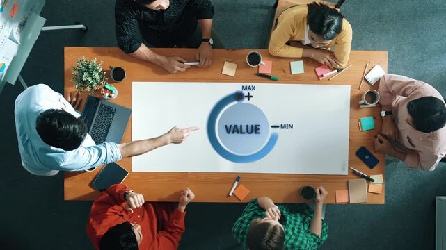A group of professionals collaborates in a modern office, focusing on strategies for value optimization while engaging in discussion and idea sharing. Raster