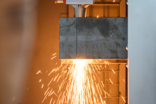 Side view of a high-precision fiber laser cut machine operation cutting a steel tube with sparkling light.