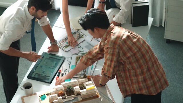 Smart architect or civil engineer writing building structure idea on note and stick on blueprint. Aerial view of manager working together with diverse colleague and show house plan. Alimentation.
