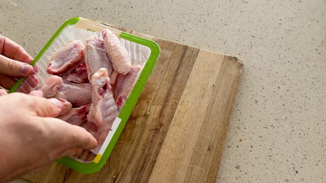 Hands Removing Liquid Absorption Pad From Raw Chicken Wing Packaging