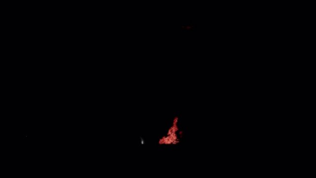 Fiery explosion with flying debris particles on black background.