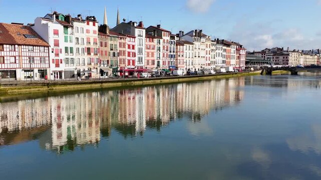 Waterfront reflection of colorful Basque architecture on the Nive river in Bayonne France, showcasing scenic old town.