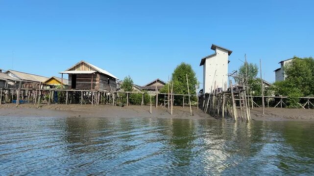 A scene depicting the life of a coastal community and its local wisdom, set against a backdrop of hills, in Rampa Cengal Village, Kotabaru Regency, South Kalimantan Province, Indonesia.