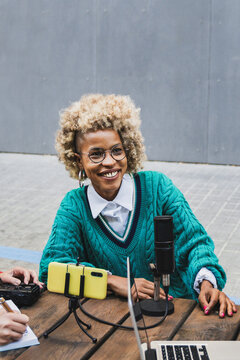 Hispanic host recording podcast interview outdoors - Afro woman doing live stream radio show - Vertical video