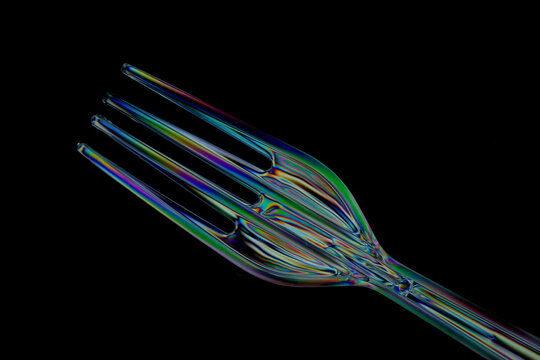 Plastic fork and spoon photographed with polarized light creating colourful stress lines