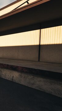 A concrete stage stands empty with a long shadow cast by the building above. The lighting shows a strong contrast between the shadow and bright areas.