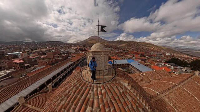 Man enjoying the scenic cityscape and Cerro Rico mountain from a historic terracotta roof in Potosi, Bolivia