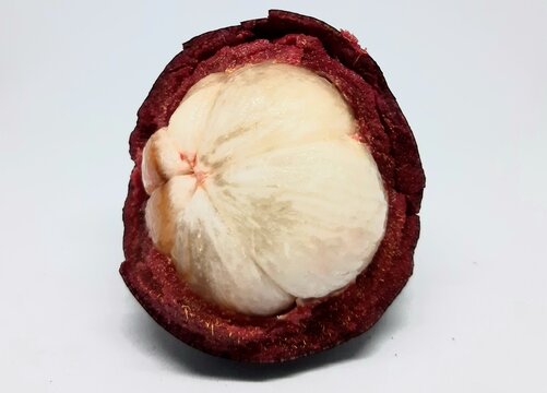 Opened ripe mangosteen revealing soft white flesh inside purple pericarp