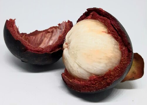 Opened ripe mangosteen revealing soft white flesh inside purple pericarp